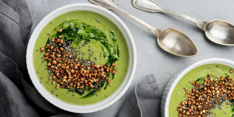 Useful smoothies from spinach with buckwheat flakes in ceramic bowls on gray concrete table background. Selective focus. Top view. Copy space