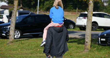 p&egrave;re portant une fillette sur ses &eacute;paules