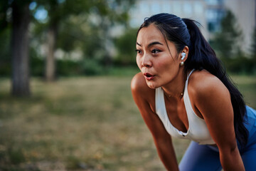Asian woman taking a moment to catch her breath after workout in park - 463592711