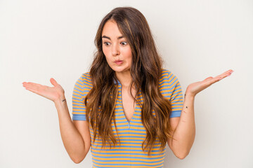 Young caucasian woman isolated on white background confused and doubtful shrugging shoulders to hold a copy space.