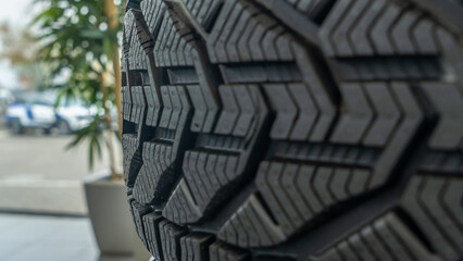 Close-up view of the winter tread of a new tire in shop. Automobile tire for snow road. Selective focus.