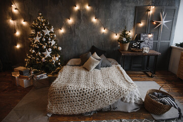 christmas bedroom interior in dark colors with a cozy large family bed decorated with a Christmas tree and decorative elements