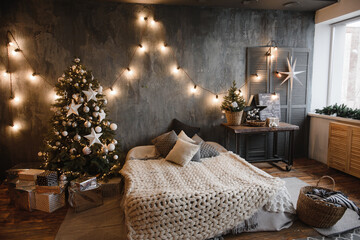 christmas bedroom interior in dark colors with a cozy large family bed decorated with a Christmas tree and decorative elements