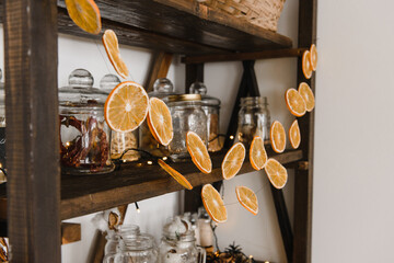 New Year's decor of the kitchen interior with an old wooden open shelf, with dishes and garlands of orange slices