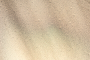 Close focus of water drop from rain on brown synthetic fabric.