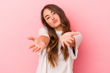 Young caucasian woman isolated on pink background folding lips and holding palms to send air kiss. © Asier