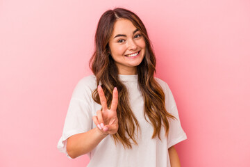 Fototapeta premium Young caucasian woman isolated on pink background showing victory sign and smiling broadly.