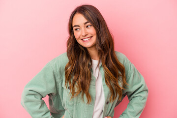 Young caucasian woman isolated on pink background confident keeping hands on hips.