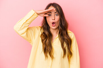 Naklejka premium Young caucasian woman isolated on pink background looking far away keeping hand on forehead.