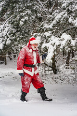 Happy Santa Claus in a traditional red costume walks through the snowy forest.