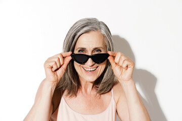 Mature woman holding sunglasses while laughing at camera