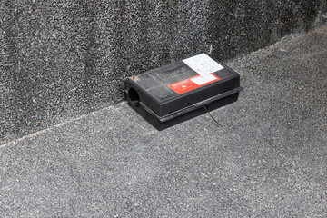 A black plastic rat trap on concrete floor. external rodent rat bait station.
