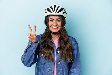 Young caucasian woman rinding a bike isolated on blue background showing number two with fingers.
