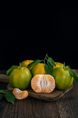 Fresh green tangerine on dark wooden table with black background.