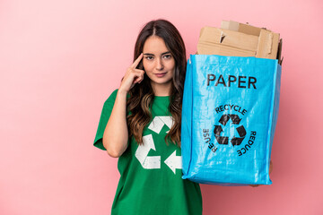 Young caucasian woman recycled paper isolated on pink background pointing temple with finger, thinking, focused on a task.