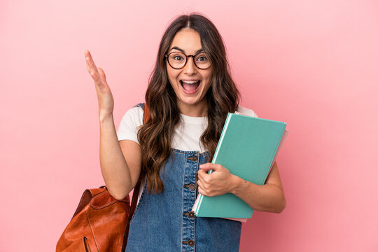Young caucasian student woman isolated on pink background receiving a pleasant surprise, excited and raising hands.