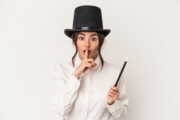 Young magician woman holding a wand isolated on white background keeping a secret or asking for silence. - obrazy, fototapety, plakaty