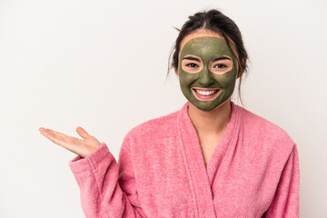 Young caucasian woman wearing a facial mask isolated on white background showing a copy space on a palm and holding another hand on waist.