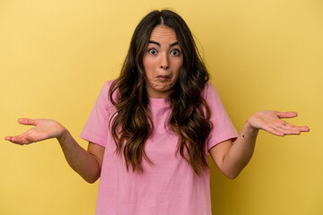 Young caucasian woman isolated on yellow background doubting and shrugging shoulders in questioning...