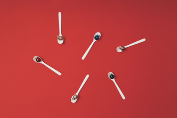 Shiny vibrant Christmas with glitter bauble decoration in a white spoon on bright red background. Christmas concept. New year minimal flat lay with copy space.