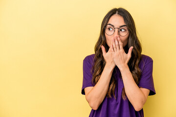 Young caucasian woman isolated on yellow background thoughtful looking to a copy space covering mouth with hand.