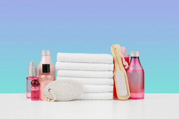 Stack of white towels and bottles of skincare on white table