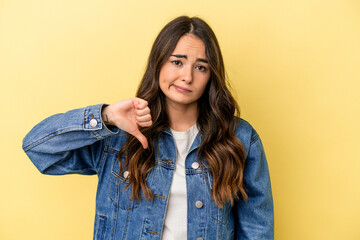 Fototapeta premium Young caucasian woman isolated on yellow background showing thumb down, disappointment concept.