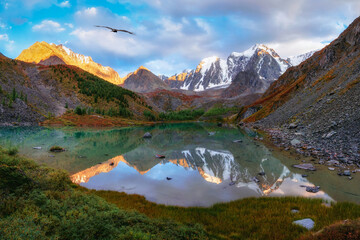 Picturesque mountain lake in the dramatic day, Altai. Beautiful reflection of mountains, sky and white clouds. Panoramic view.