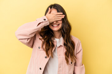 Young caucasian woman isolated on yellow background covers eyes with hands, smiles broadly waiting for a surprise.