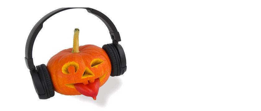 Halloween pumpkin with headphones for music on white background. Tongue out of pepper. Jack lantern from juicy pumpkin. Music for Halloween