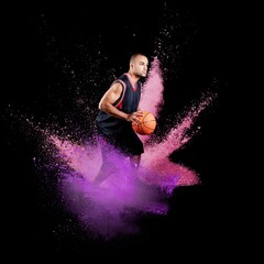 Fototapeta na wymiar High jumping. Young man, a male basketball player in explosion of colored powder
