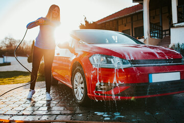 Young woman washing her carr using high pressure water. Selective focus.