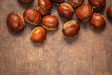 Sweet chestnuts on old rustic wooden table with plenty of copy space. Autumn fall concept. Horse chestnuts top view.