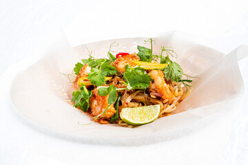 Thai style fried rice noodle with shrimp, green chives and garlic sauce, stir fry pad thai food, salt and pepper on parchment background.