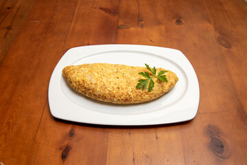 Half Spanish potato omelette with cod served in a tapas restaurant on a white tray