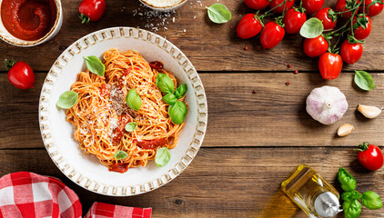 Tasty appetizing classic italian spaghetti pasta with tomato sauce, parmesan cheese and fresh basil leaves. Wooden background, top view