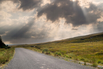 Small narrow country road in Connemara, county Galway, Ireland. Dramatic sky. Irish landscape. Beautiful nature scene