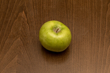 lonely green apple on a dark colored wooden table