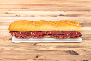 Great Spanish sandwich of smoked beef jerky sausage on white plate