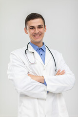 The smiling doctor stands forward with his hands folded in a gentle smile.