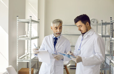 Science lab senior supervisor and young assistant discussing experiment results making conclusion...