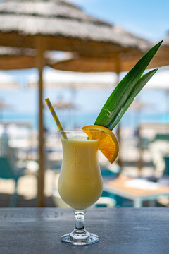 a image of a freshly made tropical piña colada cocktail with a beach front bar background