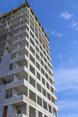 A multi-storey building under construction against a blue sky with white clouds