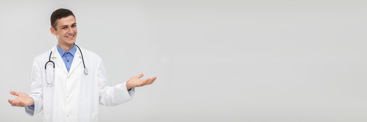 Fototapeta premium A smiling doctor spreads his arms out to the sides and leaves the choice to the patient. Panoramic view.