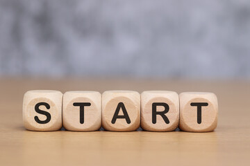 Wooden cube with the word START on the wooden floor.