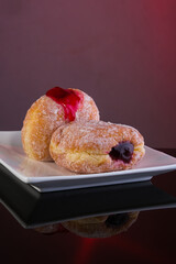 Bomboloni donuts with jam filling and icing sugar on white plate