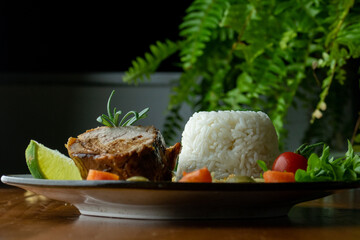 Decorated, delicious and colorful dish served with rice, salad, French fries and roast beef, close-up photo, in the background plants
