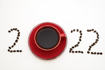 new year, numbers 2022, laid out from coffee beans on white background, red cup of coffee and coffee beans, postcard concept