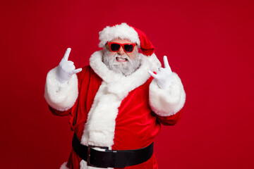 Portrait of attractive crazy Santa showing horn symbol having fun newyear occasion isolated over bright red color background