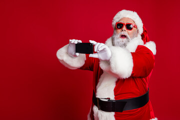 Fototapeta na wymiar Portrait of attractive bearded amazed funny Santa using device taking making selfie vlog isolated over bright red color background